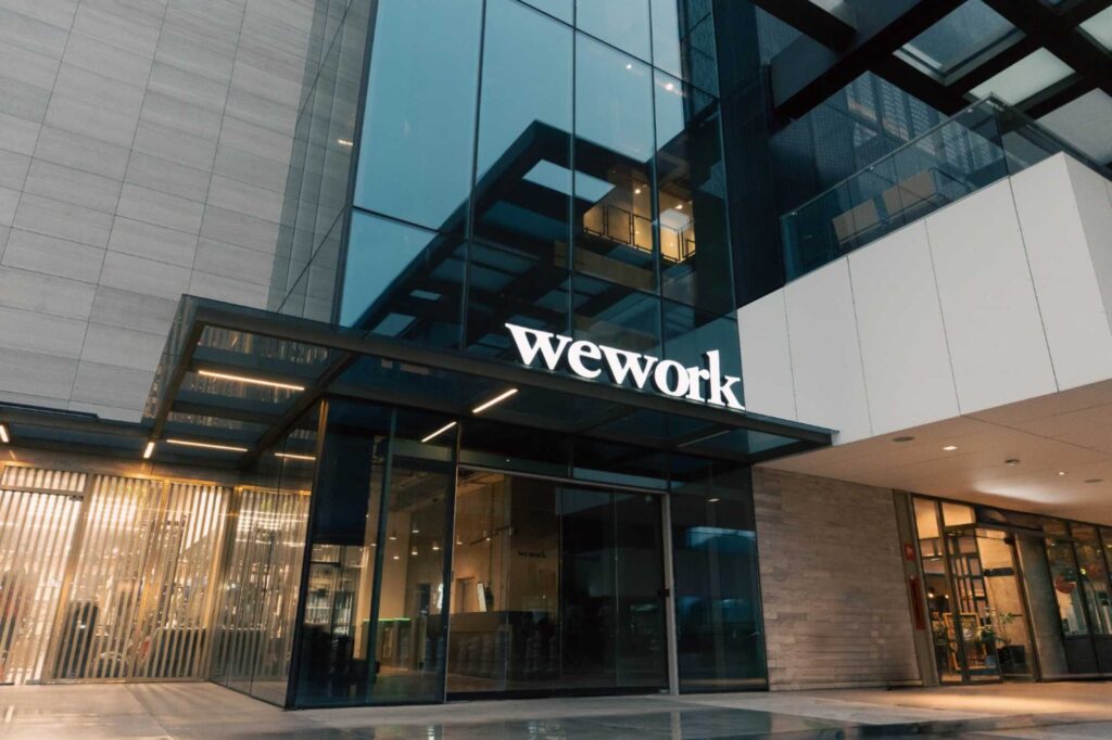 Glass-front WeWork office building with large windows and reflective facade exterior.