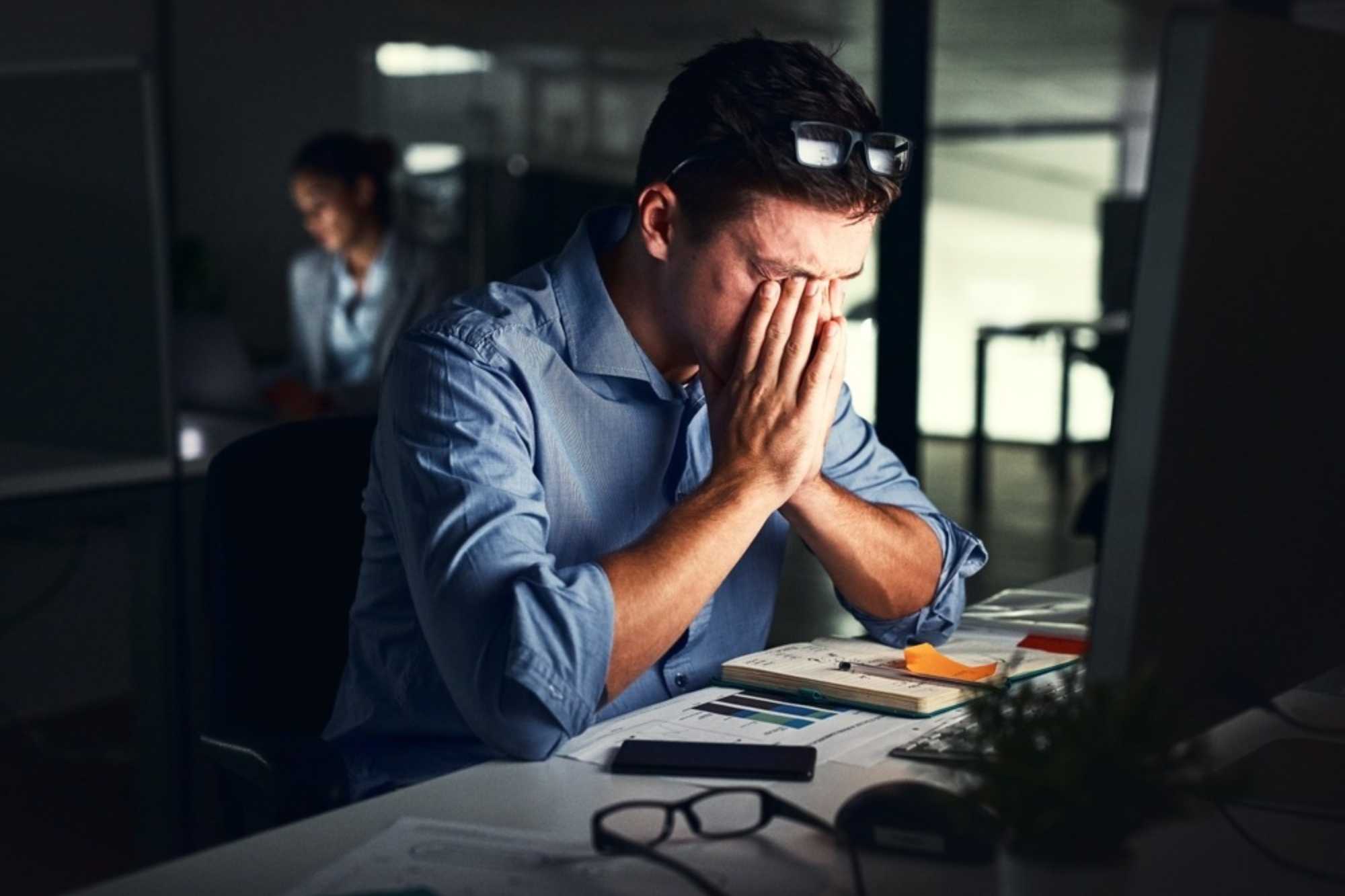 Persona agotada frente a una computadora refleja señales de desgaste y afectaciones a la salud mental en el trabajo.